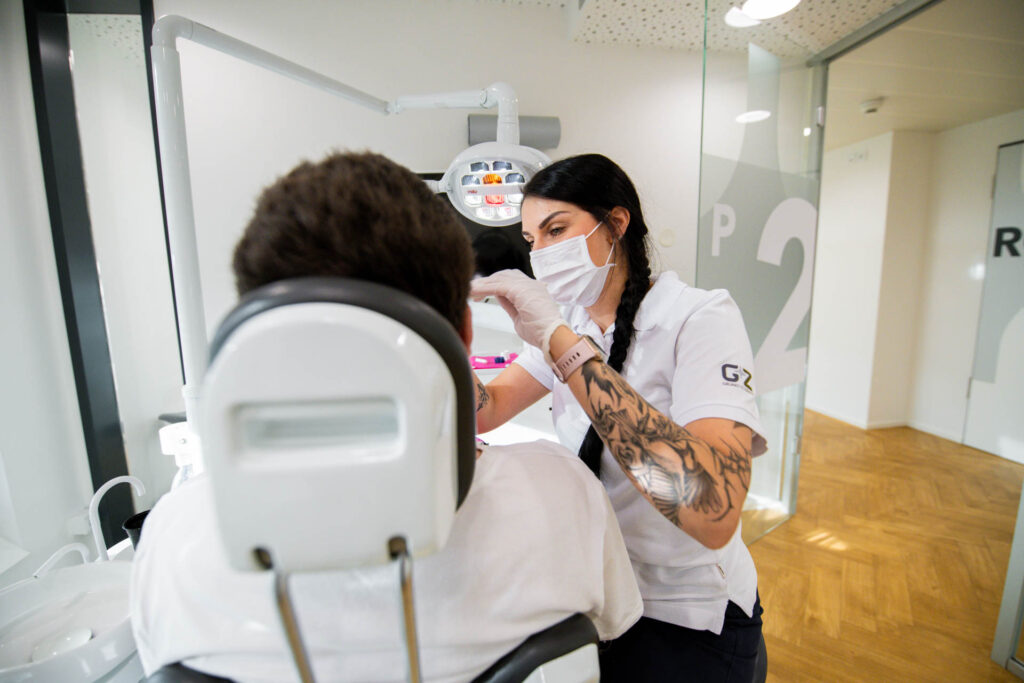 Mitarbeiterin bei GRUND UND ZÄHNE untersucht einen Patienten